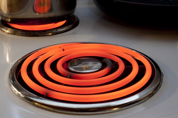 Electric stove element is on and glows bright orange.